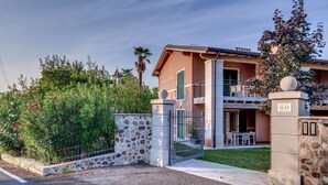 A two-story building with a stone facade, a balcony, and a gated entrance. - Tenuta di Palù (Bardolino)