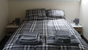 Ein Schlafzimmer mit Bett, Nachttisch, Lampe und Oberlicht.