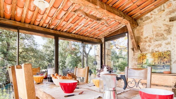 A rustic dining area with a wooden table, chairs, and a view of trees through large windows. - Wonderful private villa for 4 people with WIFI, private pool and TV (Lentier)