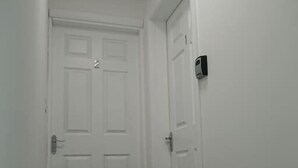 A narrow hallway with two white doors, one with a number '2' above it, and a small black device on the wall to the right. - 1 Wood Yard Cottages. 2 Bedroom, Large lounge (Long Sutton)