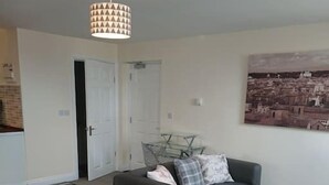 A modern living room with a grey sofa set, a dining table, and a hanging light fixture. - 1 Wood Yard Cottages. 2 Bedroom, Large lounge (Long Sutton)