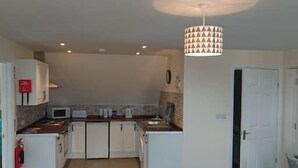 A compact living space with a kitchenette, a dining area, and a seating area with a sofa. - 1 Wood Yard Cottages. 2 Bedroom, Large lounge (Long Sutton)
