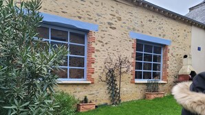 Un edificio con dos ventanas, un muro de ladrillo y un césped.