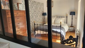 Un dormitorio con un aparador de madera, una cama con estructura metálica y dos lámparas de noche.