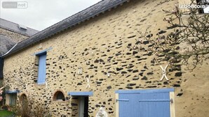 Un edificio rústico de piedra con una puerta azul y ventanas arqueadas.