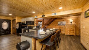 Una cucina con pareti in legno, un'isola centrale con sgabelli da bar, un frigorifero e un forno a microonde.
