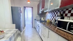 Uma cozinha compacta com armários brancos, micro-ondas e painel de parede xadrez.