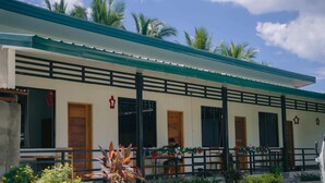 A building with a green roof, multiple doors, and a balcony with chairs. - L'Puerta Travel Inn (Hinoba-an)