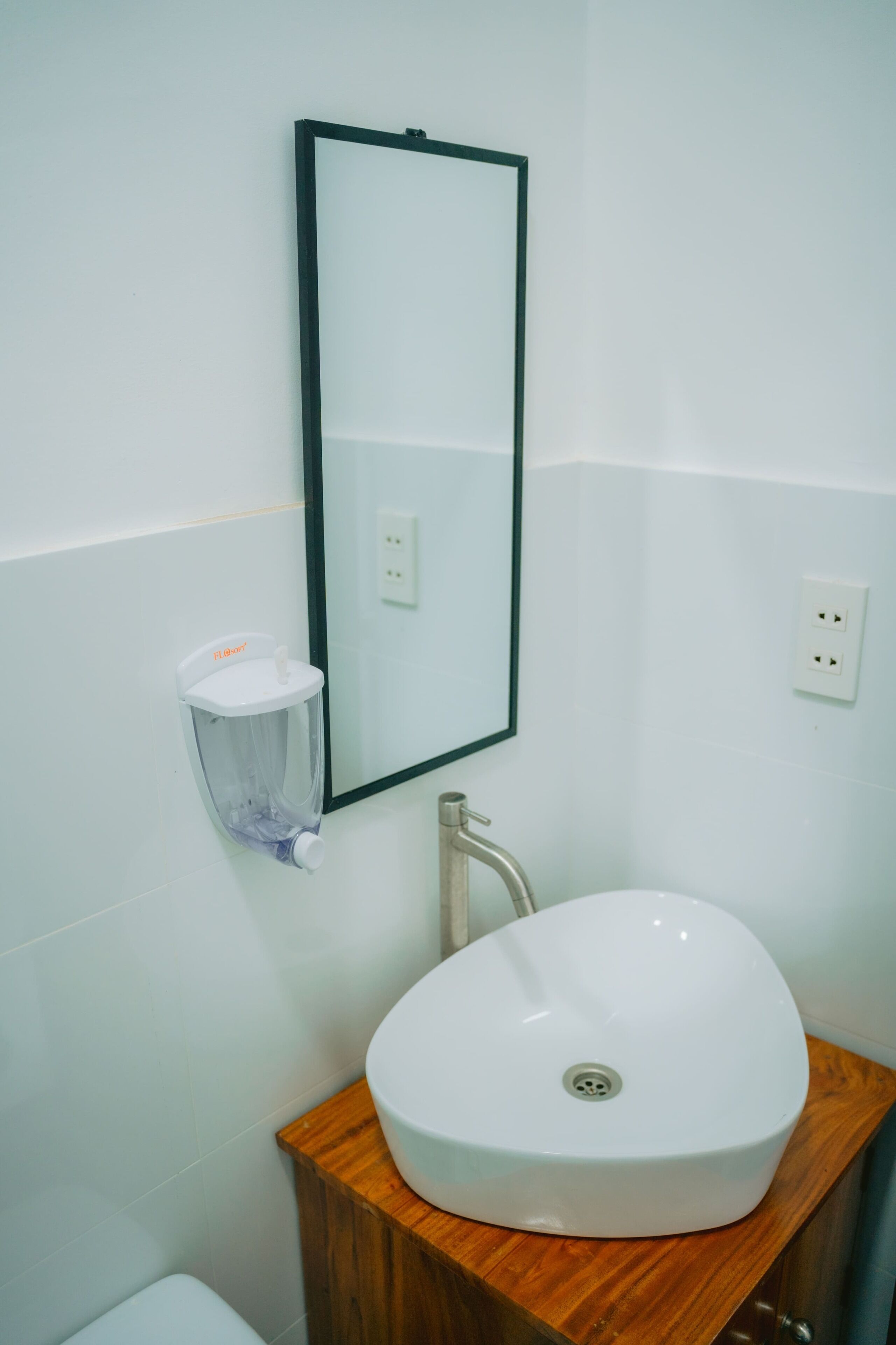 A bathroom with a white sink, wooden vanity, and a mirror.