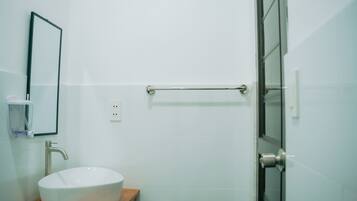 A bathroom with a white sink on a wooden countertop, a towel rack, and a glass shower door.