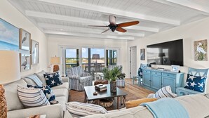 Un salon spacieux doté d’un ventilateur de plafond, de grandes fenêtres et offrant une vue sur l’extérieur.