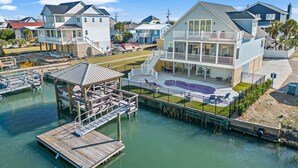 Une propriété située au bord de l’eau, avec une grande maison dotée d’un balcon, d’un quai et d’une petite piscine.