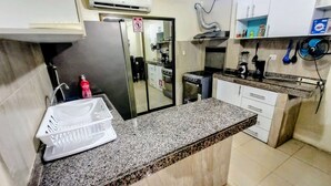 Eine Küche mit Granit Arbeitsplatten, weißen Schränken, einem Kühlschrank, einem Herd und einer Mikrowelle.