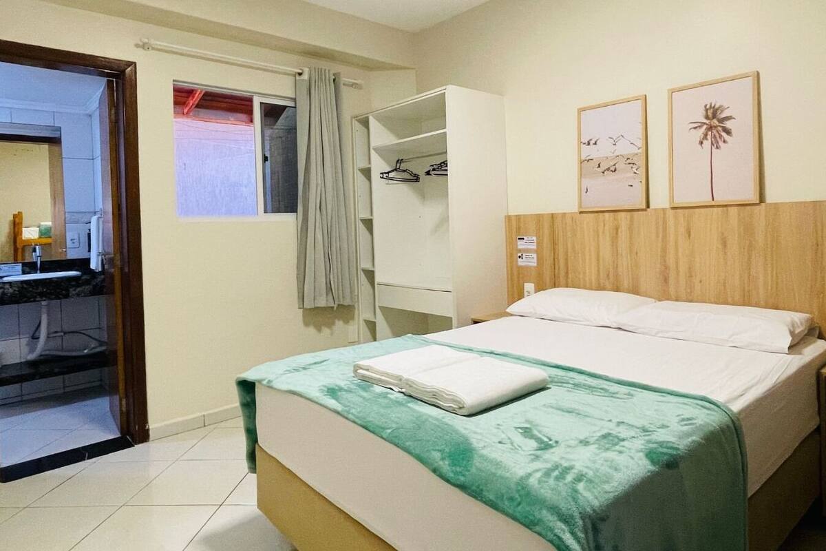 Habitación de hotel con cama, armario, baño y ventana con cortinas.