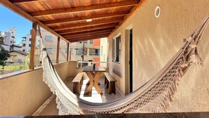A covered balcony with a hammock, wooden bench, and table. - Canto do Corrupião (Bombinhas)
