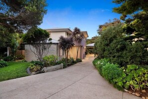 Stroll through the serene garden, surrounded by mature trees and lush greenery, to the entrance of this contemporary home.