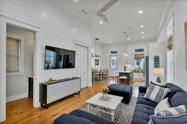 A spacious living room with a large TV, a dining area, and a kitchen.