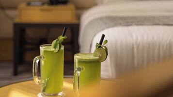Twee groene drankjes op een ronde tafel, met een bed en nachtkastje op de achtergrond.