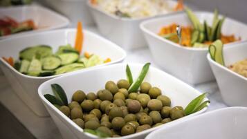A buffet table with various dishes including olives, cucumbers, and carrots.