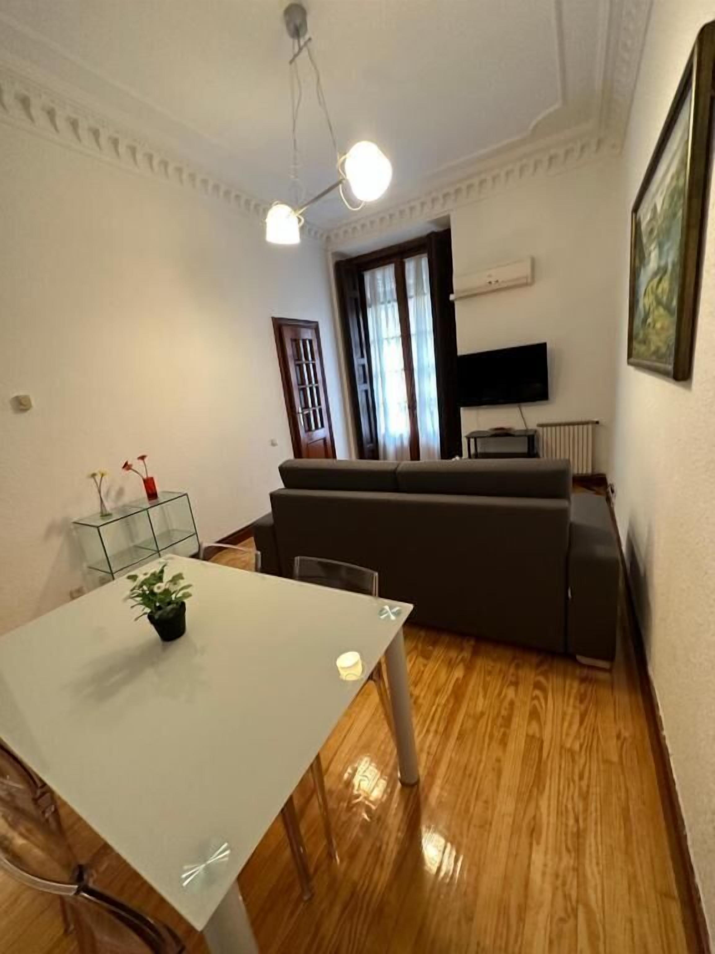 A living room with a sofa, a TV, and a dining table with chairs.