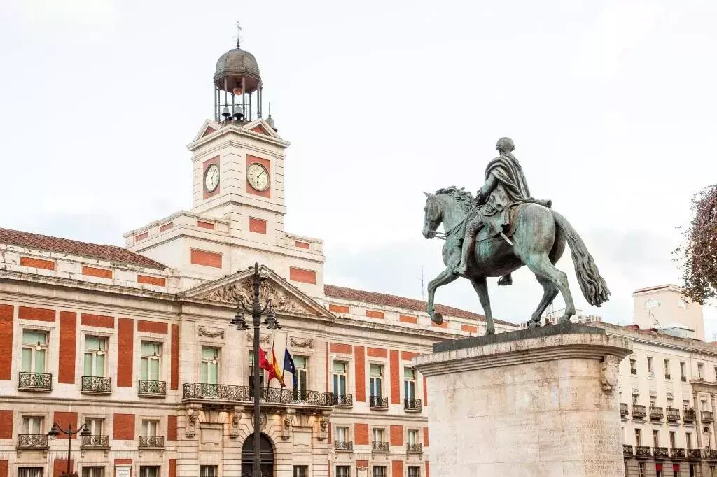 A historic building with a clock tower and a statue of a figure on horseback.