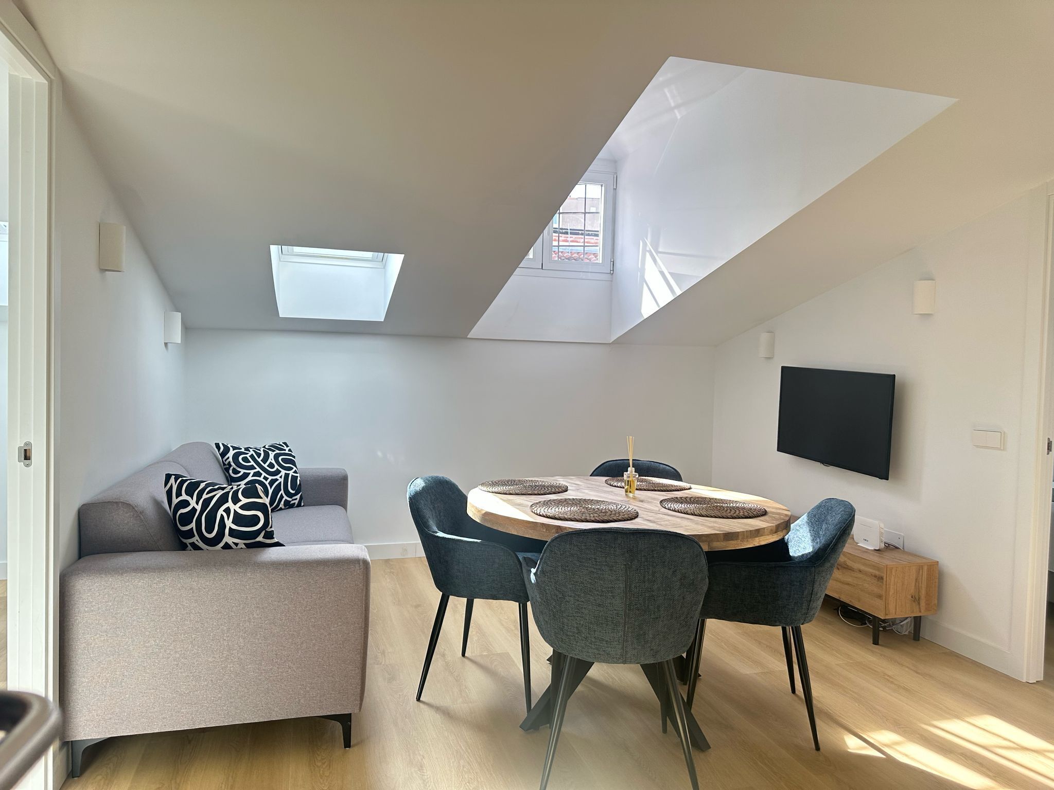 Un appartement moderne de style « loft » comprenant un coin repas, un canapé et un téléviseur.