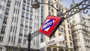 Señal de estación de Metro con una señal de nombre de calle debajo.