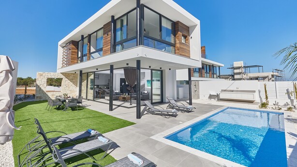 A modern two-story house with a pool, outdoor seating, and a stone wall. - Villa Elise, Stunning and Brand New 3BDR Protaras Villa with Private Pool (Protaras)
