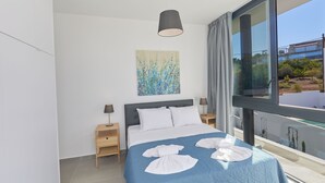 A modern bedroom with a large bed, a painting on the wall, and a view of the outside through a large window. - Villa Elise, Stunning and Brand New 3BDR Protaras Villa with Private Pool (Protaras)