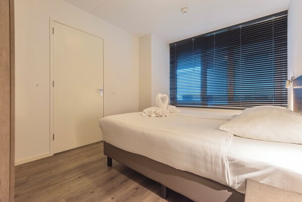Un dormitorio con cama, armario y ventana con persianas.