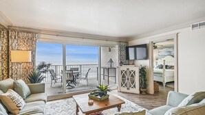 En rummelig opholdsstue med balkon, pejs og fjernsyn.