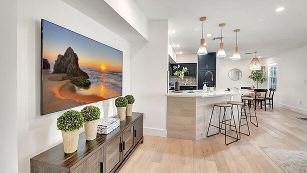 A modern kitchen with a large island, pendant lights, and a dining area with bar stools. - Palm Beach - Newly Designed come relax, shop, enjoy! (West Palm Beach)