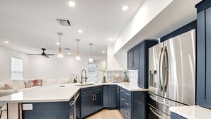 A modern kitchen with dark cabinetry, stainless steel appliances, and pendant lighting. - Palm Beach - Newly Designed come relax, shop, enjoy! (West Palm Beach)