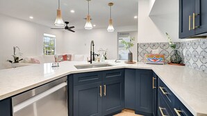 A modern kitchen with dark cabinetry, a white countertop, pendant lighting, and a ceiling fan. - Palm Beach - Newly Designed come relax, shop, enjoy! (West Palm Beach)