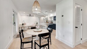 A modern kitchen with a central island, white cabinetry, and a dining area with a round table and chairs. - Palm Beach - Newly Designed come relax, shop, enjoy! (West Palm Beach)