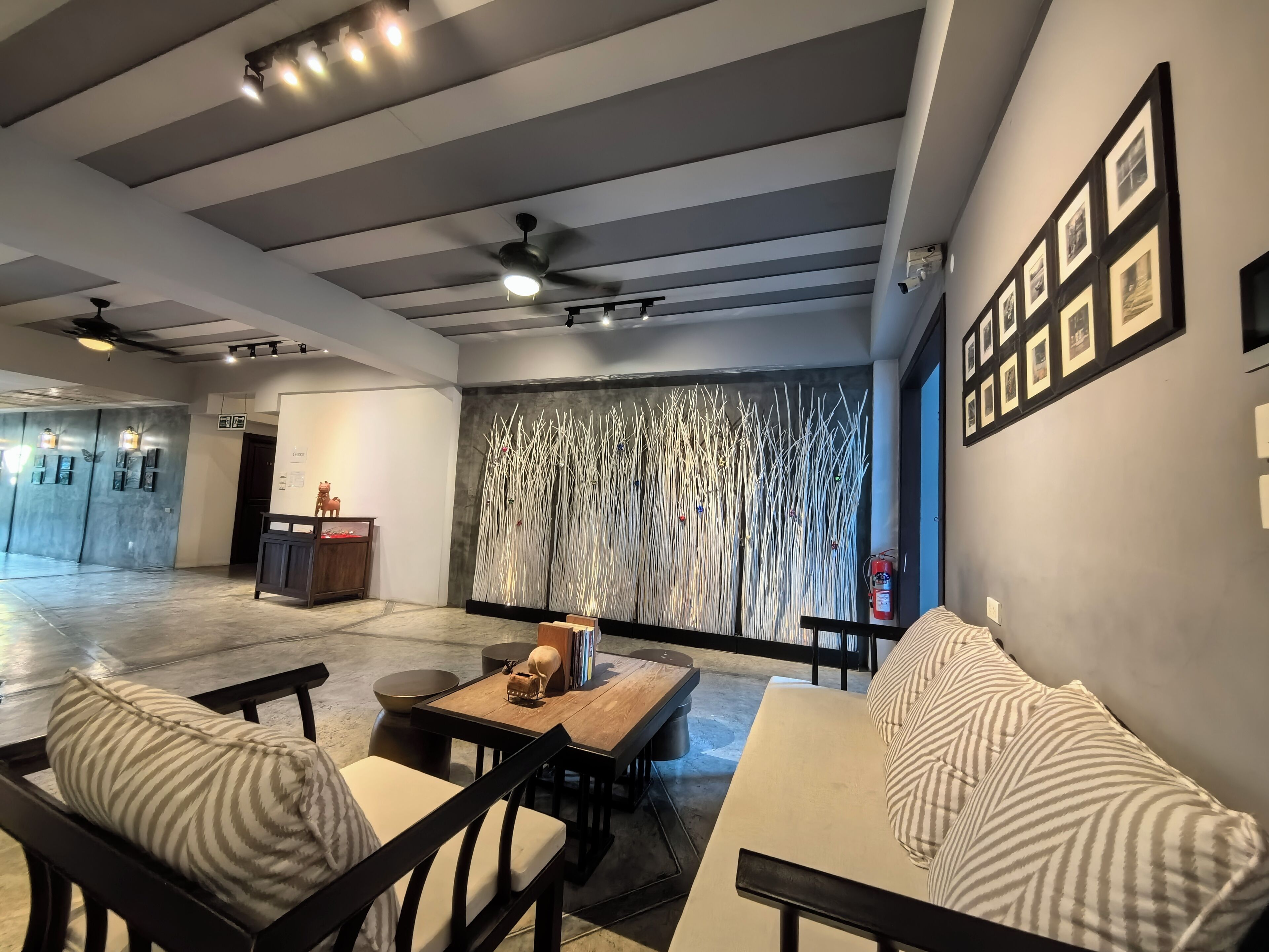 A spacious lobby with a high ceiling, ceiling fans, and a seating area with a sofa and chairs.