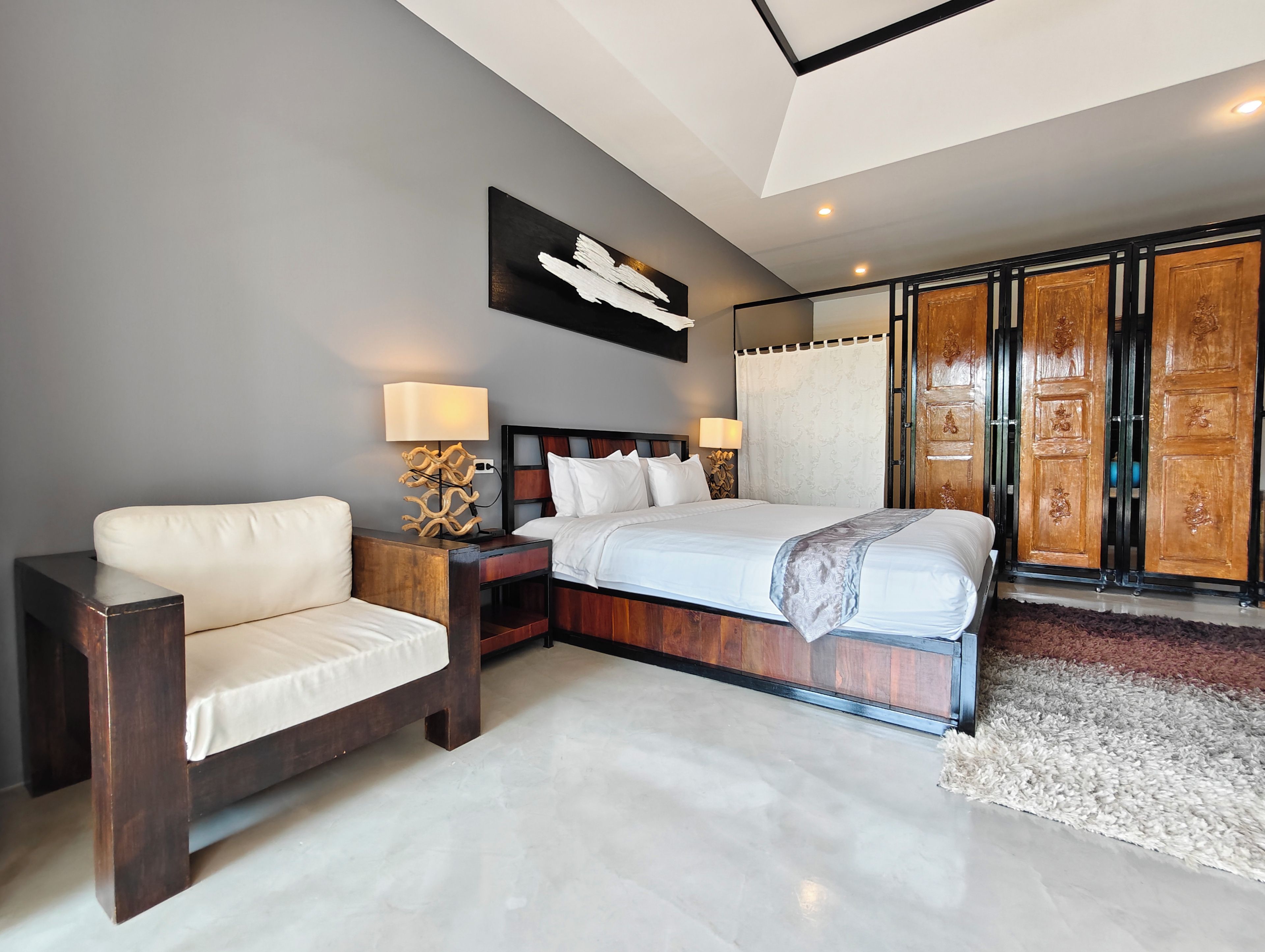 A bedroom with a bed, nightstands, a chair, a large mirror, and a wardrobe.