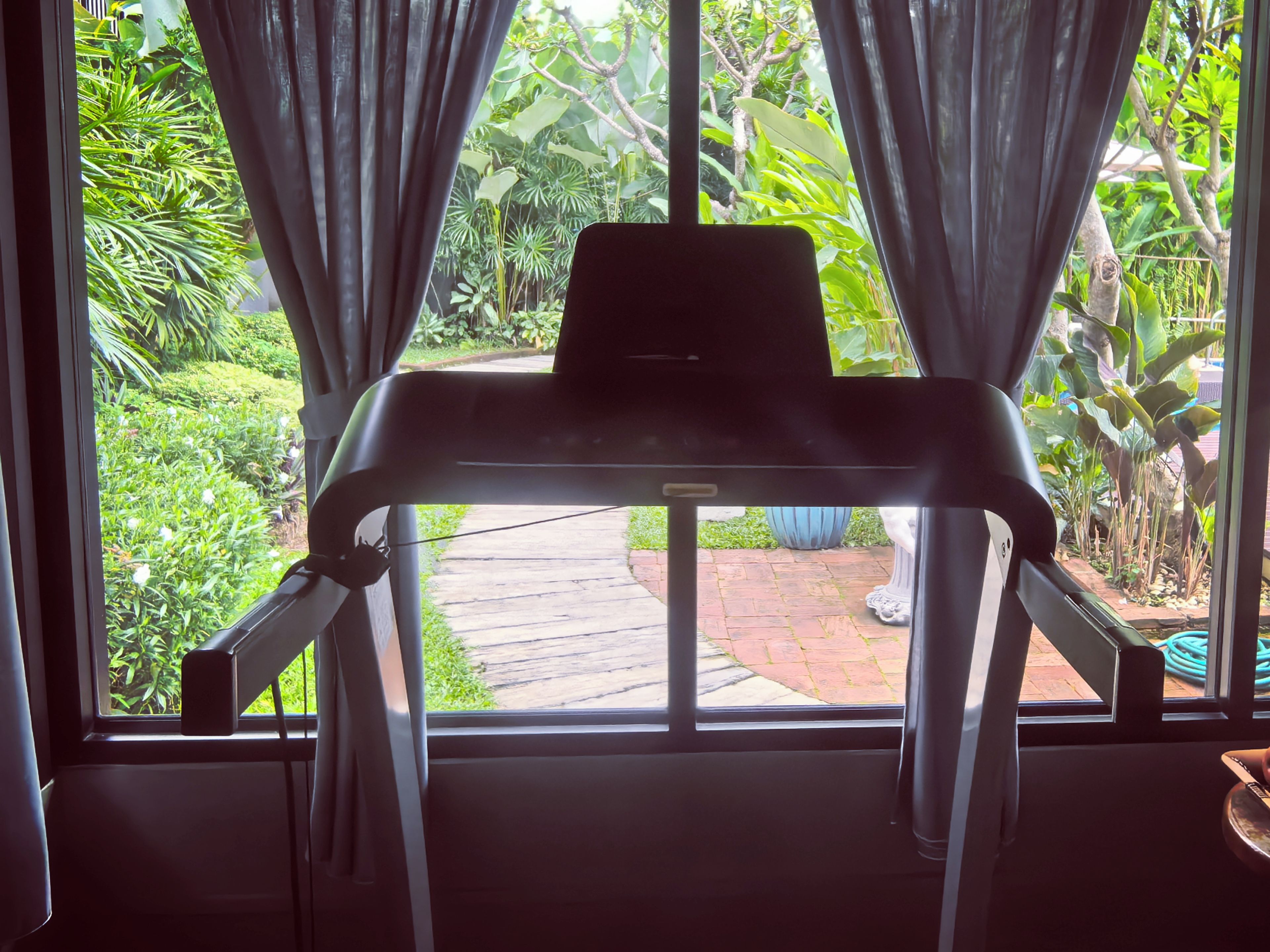 A room with a window, curtains, and a laptop on a desk.