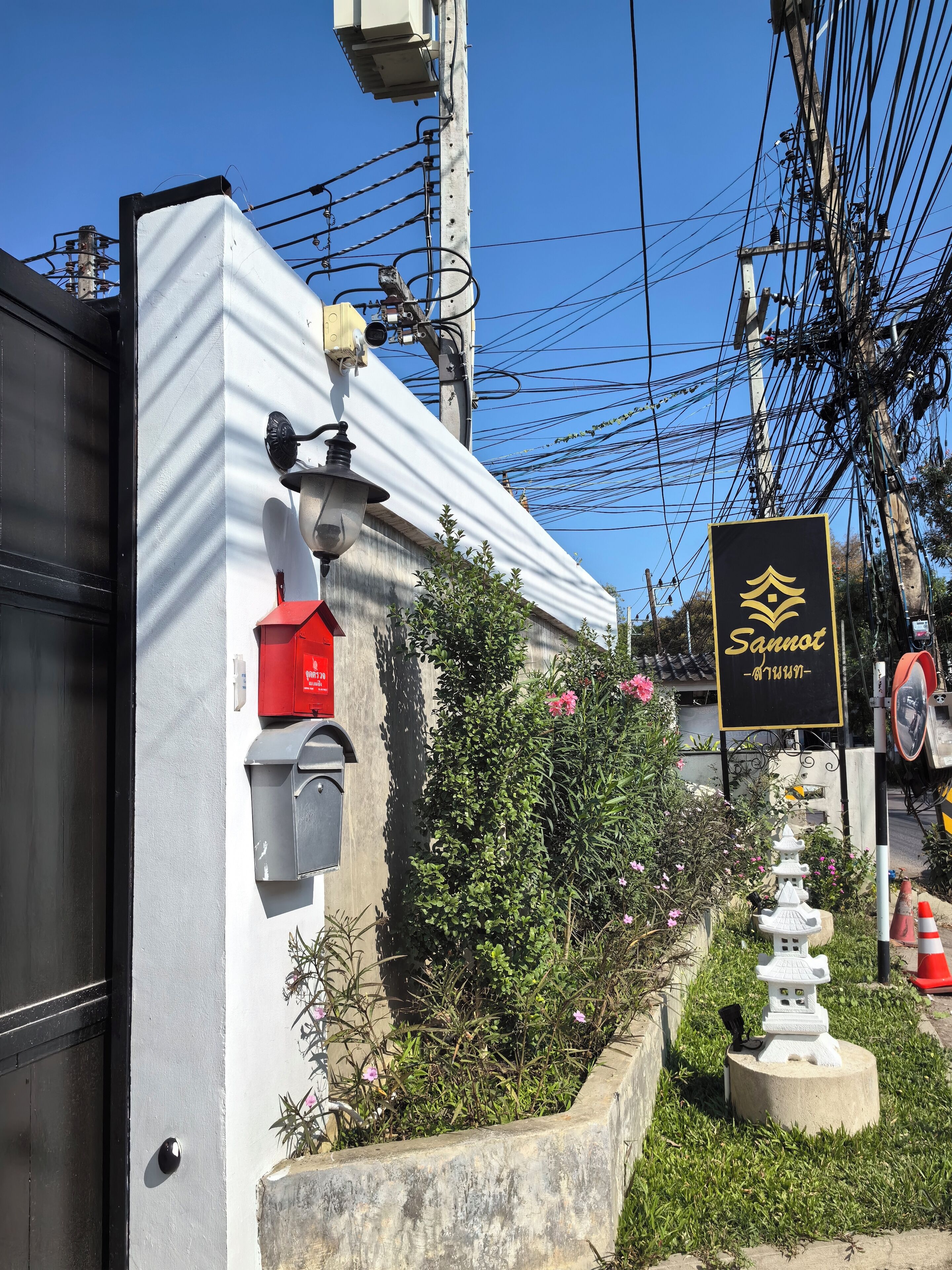 A building with a mailbox, a red fire alarm box, and a sign with a logo and text.