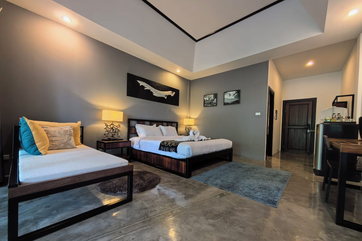 A modern bedroom with two beds, a dining area, and a kitchen.