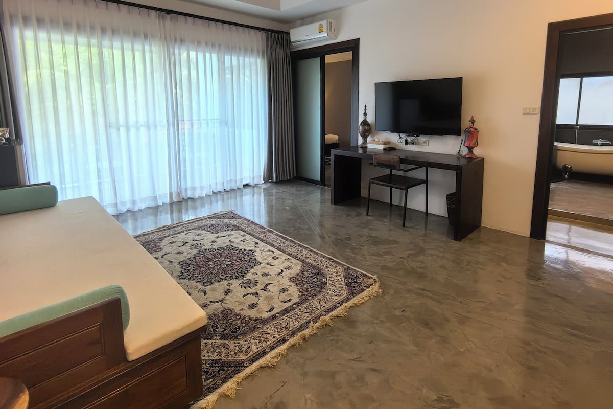 A spacious room with a bed, a desk, and a television.