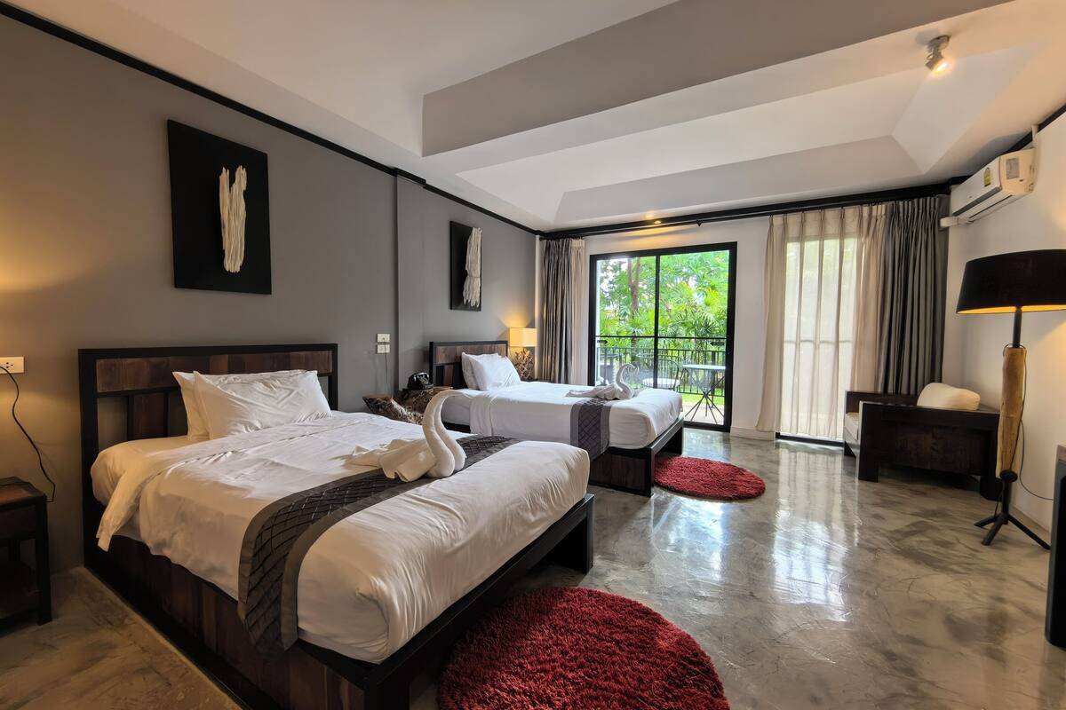 A modern hotel room with two beds, a balcony, and a red rug.