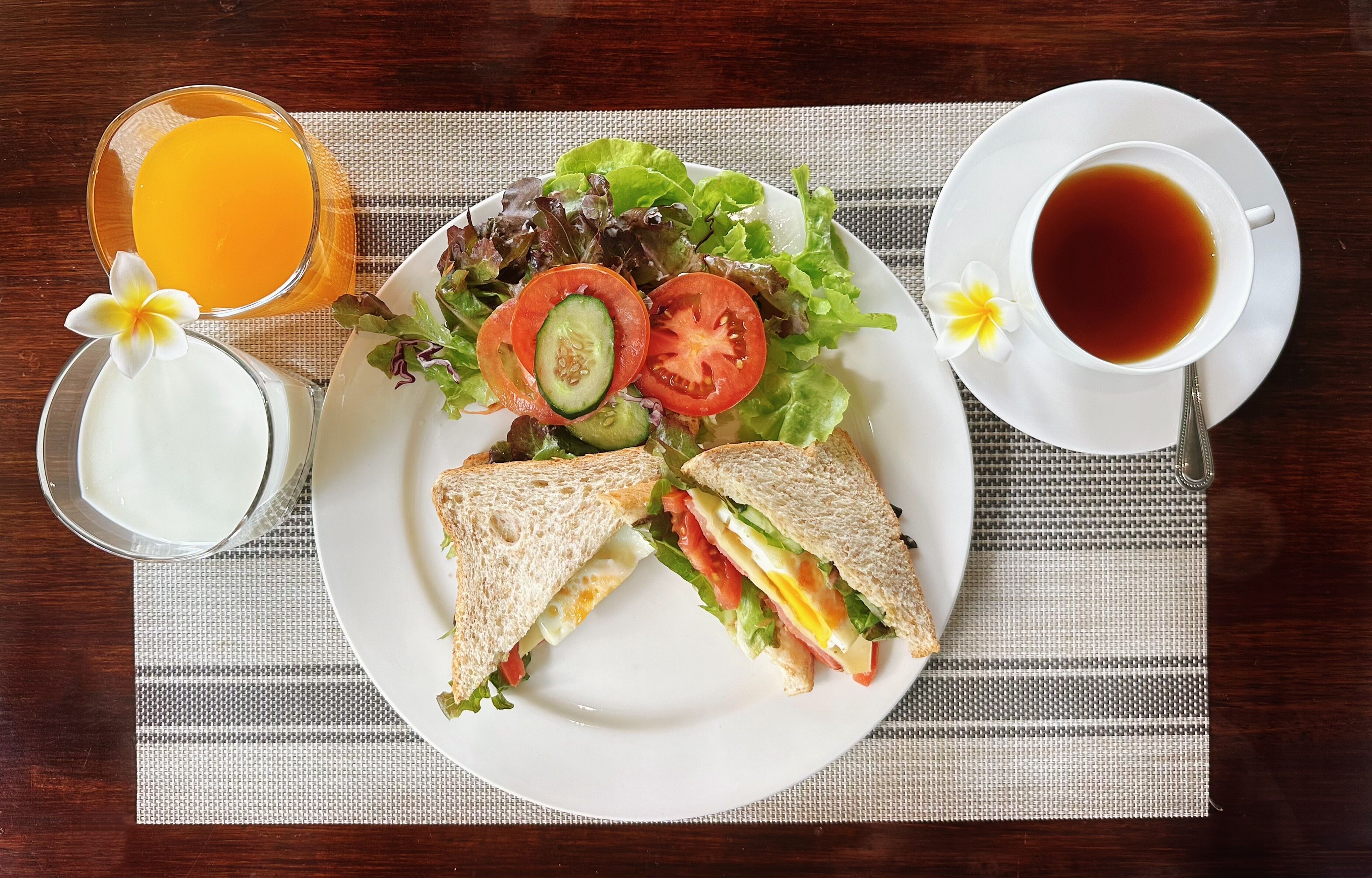 Un piatto con un panino, un'insalata e una tazza di tè su un tavolo con un sottopiatti.