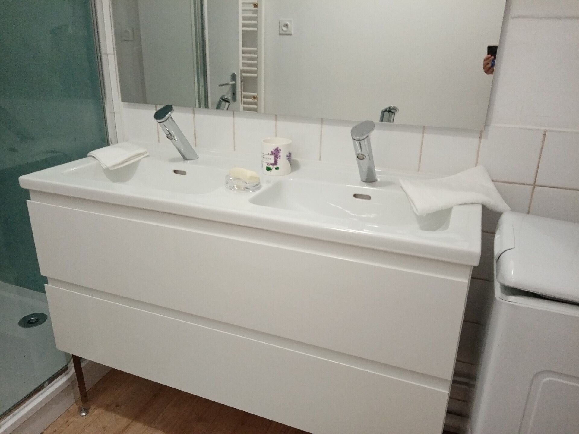 A bathroom with a white sink, two faucets, a mirror, and a toilet.