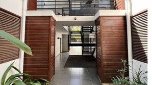 A modern building with a central courtyard, wooden paneling, and a staircase leading to an upper level. - Ô Lagon Accès Direct Plage (LA SALINE LES BAINS)