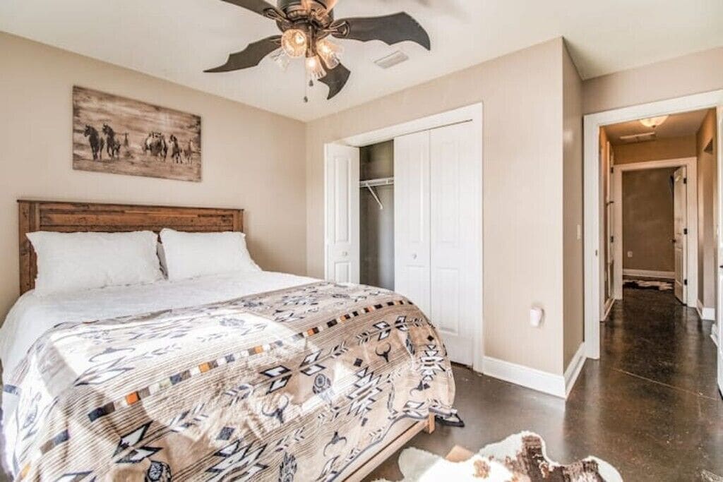 Ein Schlafzimmer mit einem großen Bett, einem Deckenventilator, einer Tür zu einem Kleiderschrank und einem Flur.