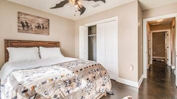 Ein Schlafzimmer mit einem großen Bett, einem Deckenventilator, einer Tür zu einem Kleiderschrank und einem Flur.