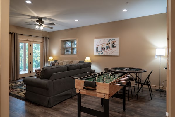 A living room with a sofa, a foosball table, and a dining table with chairs.