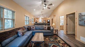 A spacious living room with a large sectional sofa, a coffee table, and a patterned rug. - New! 4BR Lake Namakagon Cabin - Sleeps 15 - Lakefront w/ boat access (Cable)