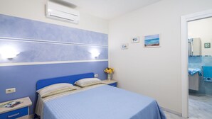 A bedroom with a bed, bedside table, and a nightstand. - Borgo dell'Uccellaia - Smeraldo (Marciana Marina)